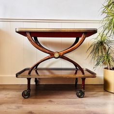 a wooden table sitting on top of a hard wood floor next to a potted plant