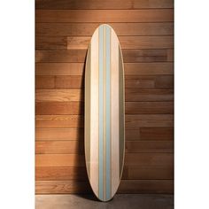 a surfboard leaning against a wooden wall in front of a wood paneled wall