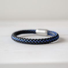 a close up of a bracelet on a table Casual Blue Durable Bracelets, Adjustable Blue Braided Bracelets For Outdoor, Modern Adjustable Blue Braided Bracelets, Modern Adjustable Blue Braided Bracelet, Adjustable Blue Leather Bracelet, Adjustable Blue Leather Bracelet For Everyday, Casual Black Braided Bracelets For Outdoor, Modern Blue Leather Bracelet, Slide Lock