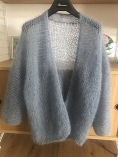 a blue cardigan sweater hanging on a rack