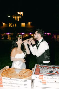 a bride and groom feeding each other pizza