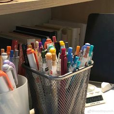 a metal basket filled with lots of pens and markers