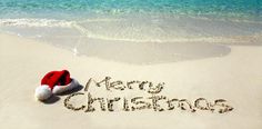 a merry christmas message written in the sand at the beach with santa's hat on it