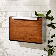 a wooden plaque mounted to the side of a white brick wall next to a green plant