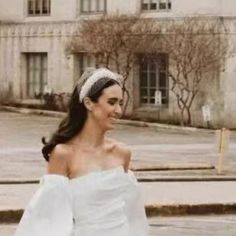 a woman in a white dress is walking down the street with her hand on her hip