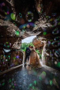 a bride and groom are standing in the middle of a tunnel with bubbles all around them