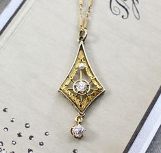 "Circa 1915, an elegant Edwardian lavaliere crafted in 14k yellow and white gold. The delicacy of the design is a perfect counterpoint to the blazing bright old mine-cut diamond set in the center, approximately .15 ct., accented by a single creamy pearl and finished with a fiery old mine-cut diamond drop, approximately .18 ct. It would be a wonderful piece for the bride who wants a romantic antique vibe; combining the gemlore of pearls and their symbolic reference to faithfulness and purity of h Art Deco Diamond Necklace With Filigree Details, Art Deco Diamond Necklace With Filigree, Art Deco White Gold Necklace With Rose Cut Diamonds, Elegant 14k Stamped Necklaces For Wedding, Art Deco Diamond Necklace In Yellow Gold, Vintage Yellow Gold Diamond Jewelry, Vintage Diamond Necklace In Yellow Gold, Yellow Gold Heirloom Jewelry, Heirloom Yellow Gold Jewelry For Vintage Events