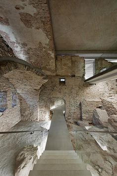 the stairs lead up to an underground passage in a stone building with concrete walls and flooring