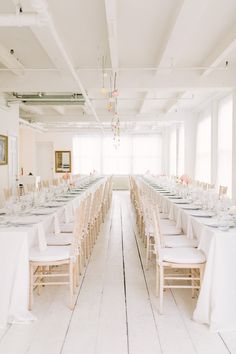 a long table set up with white linens and place settings