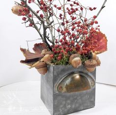 a vase filled with lots of red berries and other things on top of a table