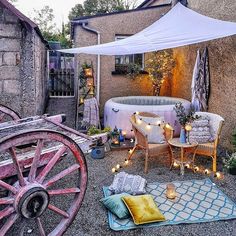 an outdoor hot tub surrounded by patio furniture and decor with candles lit on the ground