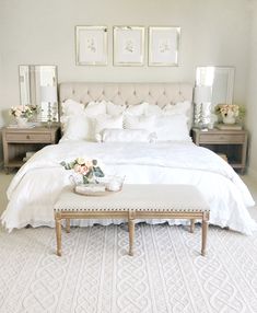 a bedroom with white bedding and flowers on the foot board in front of the bed