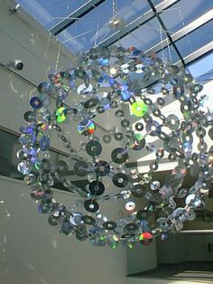 a chandelier hanging from the ceiling in front of a glass building with lots of windows