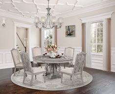 a dining room table with white chairs and a chandelier hanging from the ceiling