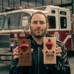 a man holding two wooden plaques in front of a fire truck