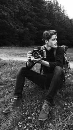 a man sitting in the grass with a camera