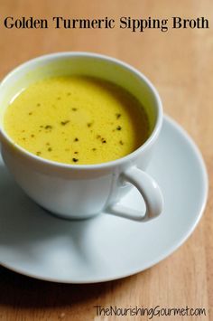 a white cup filled with yellow liquid on top of a plate