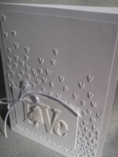 a close up of a card with hearts on the front and bottom, in white