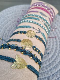 the bracelets are all different colors and have gold beads on each one, along with blue thread