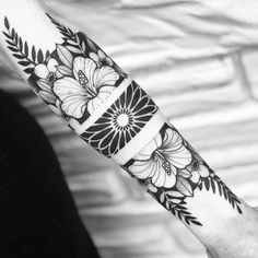 a woman's arm with flowers and leaves tattooed on the wrist, in black and white