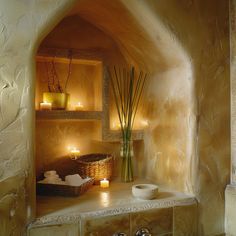 candles are lit in the corner of a room with stone walls and a basket on the counter