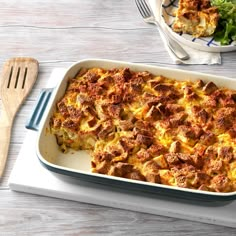 a casserole dish with meat and cheese in it next to a salad on the side