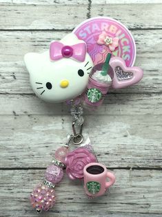 a hello kitty keychain with coffee cup and pink heart charms on it's side