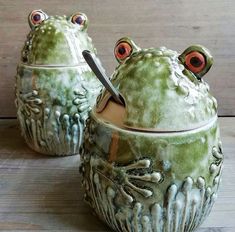 two green ceramic pots with red eyes and one has a knife sticking out of it