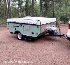 a camper trailer parked next to a white car