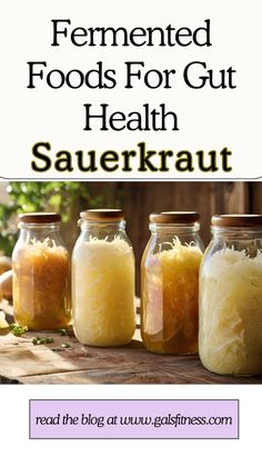 four jars filled with sauerkraut on top of a wooden table next to an apple