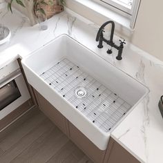 a white kitchen sink sitting under a window next to a faucet and dishwasher