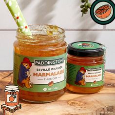 two jars of marmalade sitting on top of a wooden table