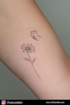 a small tattoo on the arm of a woman with two daisies and a butterfly