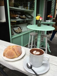 there is a cup of coffee and a loaf of bread sitting on the table outside