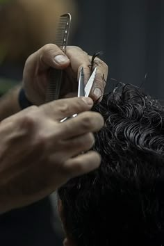 a person cutting another persons hair with scissors