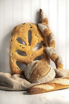 a loaf of bread and a baguette sit on a towel next to a white wall