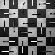 black and white checkered chess board with nails stuck in the middle on it's surface