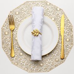 a white plate topped with a napkin and gold utensils next to a fork