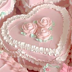 a heart shaped cake with pink frosting and roses on the top is surrounded by other cakes