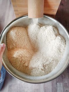 a person pours flour into a metal bowl