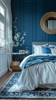 a bedroom with blue walls and white bedding in the corner, along with a round mirror on the wall