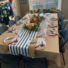 a long table with place settings and plates on it in front of a large window