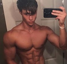 a shirtless man taking a selfie in front of a mirror with his cell phone