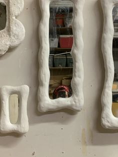 three mirrors are hanging on the wall in front of each other, one is made out of clay