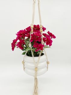 a white hanging planter with red flowers in it