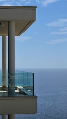 a balcony overlooking the ocean on a sunny day with blue sky and water in the background