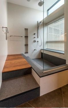 a bathroom with a wooden counter top next to a walk in shower and built - in shelving