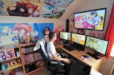 a man sitting at a computer desk in front of two monitors with anime wallpapers on the walls