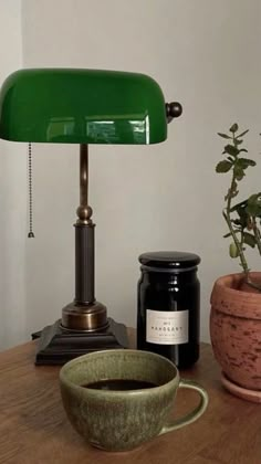 a green lamp sitting on top of a wooden table next to a potted plant