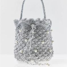 a crocheted bag with pearls on the handle and handles, sitting on a white surface